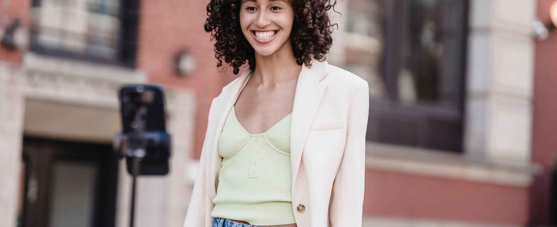 positive ethnic woman in white elegant jacket having online conversation